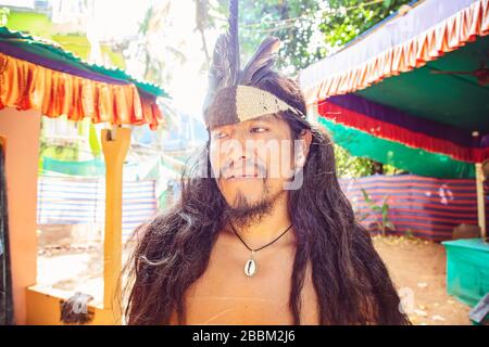 Outdoor-Porträt des jungen amerikanischen Mannes mit langen schwarzen Haaren und indischer Kopfbesinnen Stockfoto