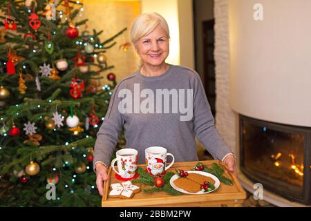 Ältere Frau mit Tablett mit Weihnachtsgebäck Stockfoto