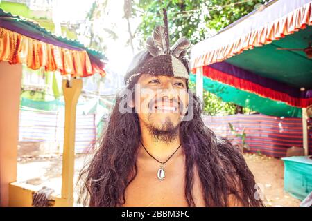 Outdoor-Porträt des jungen amerikanischen Mannes mit langen schwarzen Haaren und indischer Kopfbesinnen Stockfoto