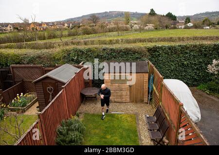 James Campbell, 31, der in seinem Garten in Cheltenham, Gloucestershire, während er sich im Lockdown befindet, einen 26,2 Meilen langen Marathonkurs führt. Stockfoto