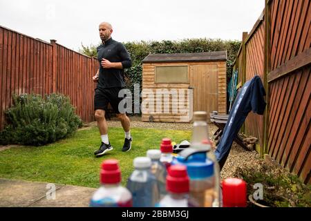 James Campbell, 31, der in seinem Garten in Cheltenham, Gloucestershire, während er sich im Lockdown befindet, einen 26,2 Meilen langen Marathonkurs führt. Stockfoto