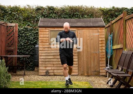 James Campbell, 31, der in seinem Garten in Cheltenham, Gloucestershire, während er sich im Lockdown befindet, einen 26,2 Meilen langen Marathonkurs führt. Stockfoto