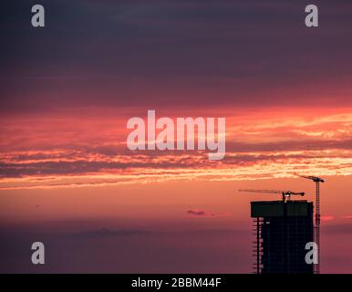 Baustelle und Kran gegen bunten Himmel. Baukonzept. Stockfoto