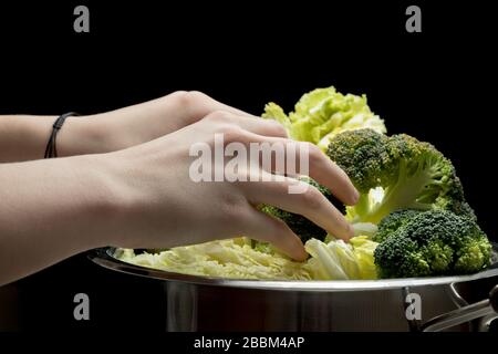 Frauen Hände halten Brokkoli und machen Low-Carb-Diät-Mahlzeit. Junge Hausfrau, die Rohkost vorbereitet. Stockfoto