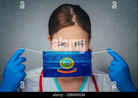 Coronavirus in US-Bundesstaat Idaho, Female Doctor Portrait, Protect Face Surgical Medical mask with Idaho Flag. Krankheit, Virus Covid-19 in Idaho Stockfoto