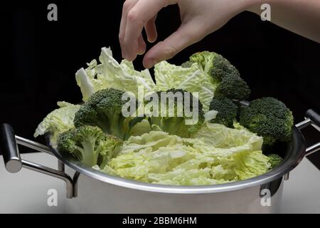 Frauen Hände halten Brokkoli und machen Low-Carb-Diät-Mahlzeit. Junge Hausfrau, die Rohkost vorbereitet. Stockfoto