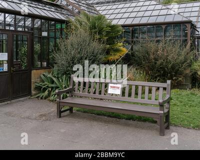 Bänke in den Botanischen Gärten, die Hinweise haben, die Menschen dazu ermutigen sollen, sich bei der Nutzung des Parks sozial zu distanzieren und die Nutzung von Sitzbänken während der britischen Coronavirus Pandemie zu entmutigen. Stockfoto