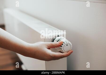 Nahaufnahme und Frau, die die Heizung am Kühler im Winter, im Frühling und beim Energieverbrauch manuell regelt Stockfoto