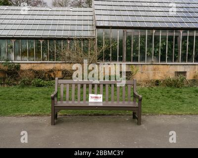 Bänke in den Botanischen Gärten, die Hinweise haben, die Menschen dazu ermutigen sollen, sich bei der Nutzung des Parks sozial zu distanzieren und die Nutzung von Sitzbänken während der britischen Coronavirus Pandemie zu entmutigen. Stockfoto