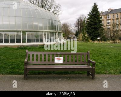 Bänke in den Botanischen Gärten, die Hinweise haben, die Menschen dazu ermutigen sollen, sich bei der Nutzung des Parks sozial zu distanzieren und die Nutzung von Sitzbänken während der britischen Coronavirus Pandemie zu entmutigen. Stockfoto