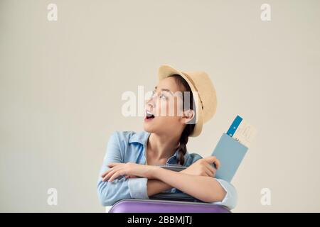 Überfreudiger Tourist, der abseits schaut und Tickets hält, grauer Hintergrund, freier Platz. Stockfoto