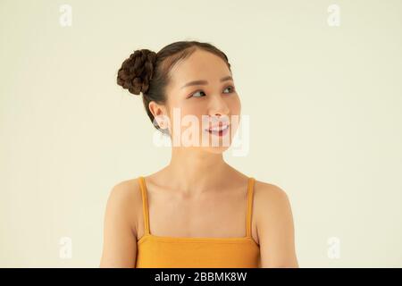 Porträt des jungen süßen asiatischen Mädchens mit zwei Brötchen vor hellem Hintergrund. Stockfoto