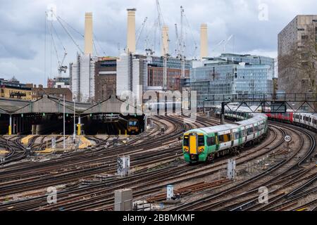 Ein Südzug, der zum Bahnhof Victoria London mit Battersea Power Station im Hintergrund eintrifft Stockfoto