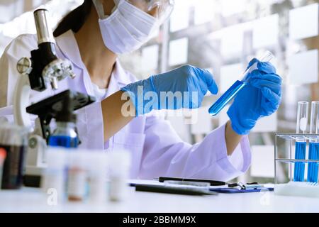 Wissenschaftler tragen Labormantel und Schutzkleidung arbeiten mit Forschung oder machen Untersuchungen mit Reagenzgläsern in Experiment, Labor und Entwicklung Stockfoto