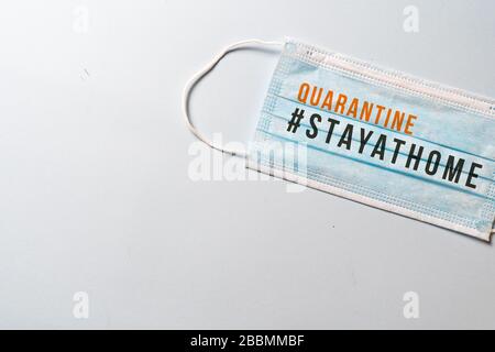 #STAYATHOME. Chirurgische Maske mit der Meldung "TAG ZU HAUSE - QUATANTINE"., COVID-19, Virenschutz und Quarantäne-Minimalkonzept. Weißer Backgr Stockfoto