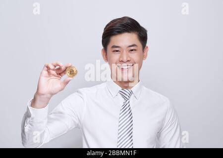 Junger gutaussehender Geschäftsmann, der Bitcoin über isoliertem weißem Hintergrund hält Stockfoto