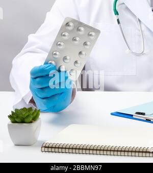 Männliche Hand mit blauen sterilen Handschuhen hält einen Stapel Pillen in einer Blase, Konzept für die medikamentöse Behandlung von Krankheiten Stockfoto