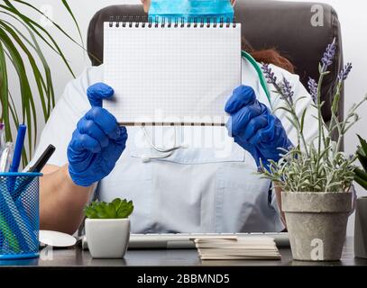 medic Woman in weißem Mantel, blaue Latexhandschuhe, die ein offenes Notizbuch mit leeren weißen Blättern, weißem Hintergrund, Platz für Text halten Stockfoto