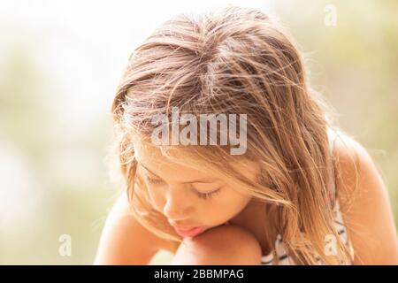 Kleines blondes Mädchen mit Kopf verbeugt, nach unten blickend Stockfoto