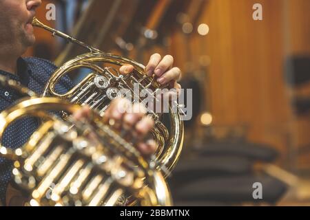 Mann, der während des philharmonischen Konzerts, der Kunst und des Konzerts auf dem französischen Horn spielt Stockfoto