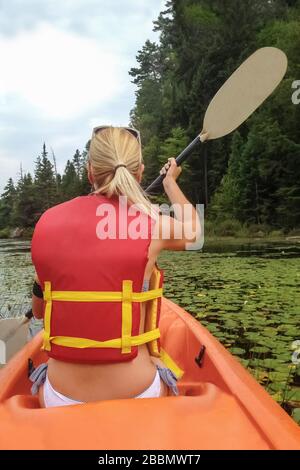 Mädchen Kajakfahren auf dem See mit Seerosen Stockfoto