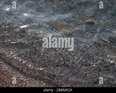 Transparentes Wasser am Ufer des Kieselstrands Stockfoto