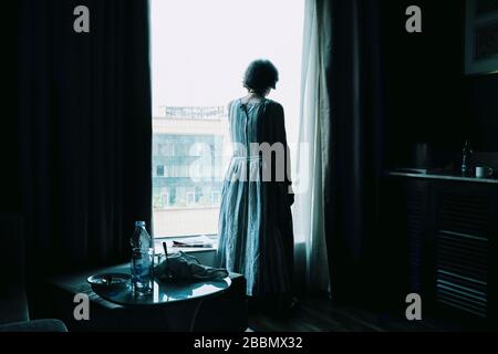 Eine alte Dame, die allein auf unser Fenster blickt. Stockfoto