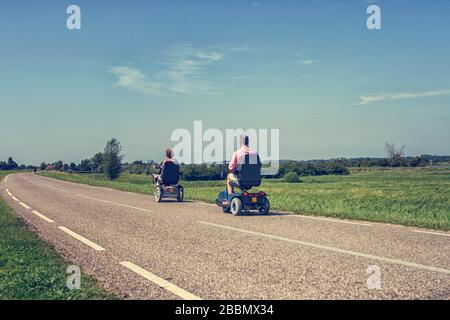 Paar in motorisierte Rollstühle auf einer Straße in den Niederlanden im Sommer Stockfoto