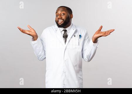 Coronavirus, Kovid19 und Gesundheitskonzept. Ich weiß nicht, dass es mir leid tut. Porträt des widerstrebenden, unbestörten afroamerikanischen Arztes Shrugging Stockfoto