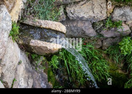 Ein kleiner Wasserfall, der aus der Quelle von Sataf in ein uraltes Speicherbecken fällt, am Fuß einer verlassenen Altstadt, früher zur Bewässerung und zum Waschen von Kl Stockfoto