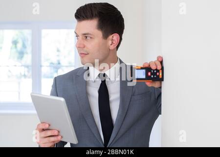 Männliche Realtor mit digitalen Tablet Messraum mit Laser messen. Stockfoto