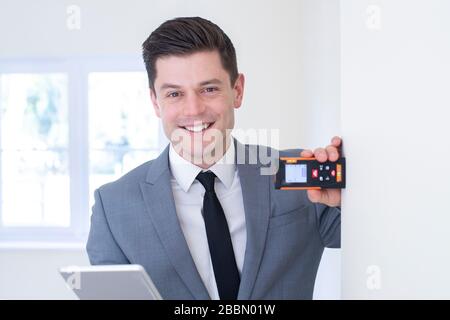 Porträt Des Männlichen Realtors Mit Digitalem Tablet-Messraum Mit Lasermaß Stockfoto