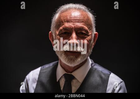 Porträt eines lächelnden Seniors auf schwarzem Hintergrund. Stockfoto