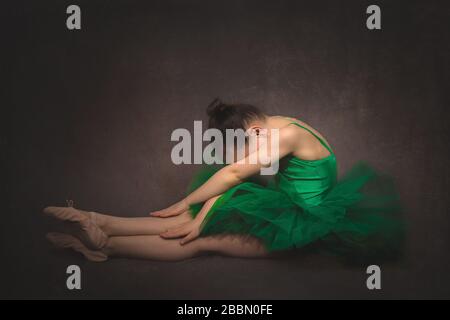 Junge Balletttänzerin in einem Studio mit grünem Tutu und braunem Hintergrund, Northamptonshire, England Stockfoto