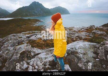 Touristin in Norwegen geht in die Berge Urlaub Abenteuer im Freien Lifestyle-Mädchen mit gelbem Regenmantel erkunden Lofoten Inseln Stockfoto