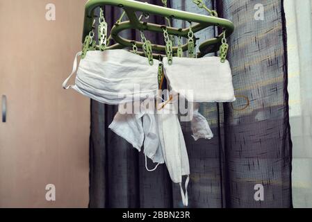 Hausgemachte Gesichtsschutzmasken hängen nach dem selektiven Fokus der Wäsche in der Halle Stockfoto