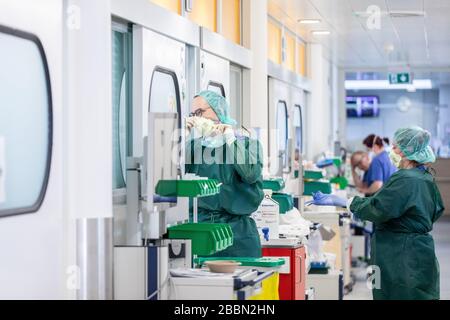 Essen, Deutschland. April 2020. Krankenschwestern kleiden sich in Schutzkleidung vor einem Krankenhauszimmer in der Intensivstation des Universitätsklinikums Essen, in dem ein Corona-Patient aus Frankreich behandelt wird. Heute wurden weitere schwer an Covid-19 erkrankte Patienten von Frankreich nach Essen geflogen. Credit: Marcel Kusch / dpa / Alamy Live News Stockfoto