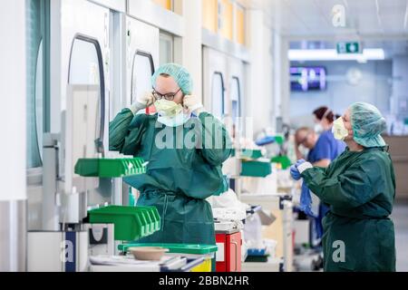 Essen, Deutschland. April 2020. Krankenschwestern kleiden sich in Schutzkleidung vor einem Krankenhauszimmer in der Intensivstation des Universitätsklinikums Essen, in dem ein Corona-Patient aus Frankreich behandelt wird. Heute wurden weitere schwer an Covid-19 erkrankte Patienten von Frankreich nach Essen geflogen. Credit: Marcel Kusch / dpa / Alamy Live News Stockfoto