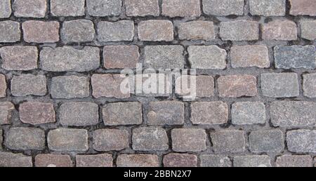 Altes Kopfsteinpflaster. Blick über die Decke von grauen rechteckigen Steinen. Hintergrundtextur, Nahaufnahme. Stockfoto