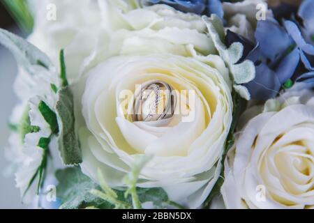 Hochzeitsringe und Blumen schließen sich vor der Zeremonie Stockfoto