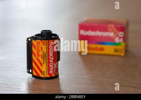 Rollen und Schachtel von Kodachrome 64, 35-mm-Dia-Film auf einem Tisch. Der bekannteste Transparenzfilm im 20. Jahrhundert. Fokus auf Vordergrund. Stockfoto