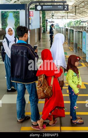 Eine indonesische Familie wartet auf der Station Platform, während SICH EIN Zug nähert, die Metro (MRT), Jakarta, Indonesien. Stockfoto