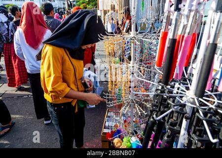 Eine junge Frau betrachtet Schmuck auf EINEM Stall auf EINEM Straßenmarkt im Kota District, Jakarta, Indonesien. Stockfoto