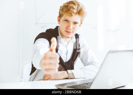 Junger Geschäftsmann, der im Büro am Laptop arbeitet Stockfoto