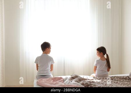 Junge und Mädchen sitzen auf dem Bett in einer Entfernung voneinander. Stockfoto