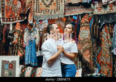 Ein Paar in Liebeswanderungen und Umarmungen auf dem östlichen Teppichmarkt. Ein Mann und eine Frau wählen einen türkischen Teppich Stockfoto