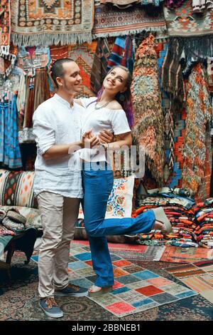 Ein Paar in Liebeswanderungen und Umarmungen auf dem östlichen Teppichmarkt. Ein Mann und eine Frau wählen einen türkischen Teppich Stockfoto