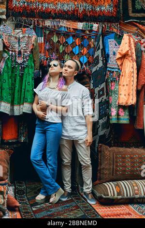 Ein Paar in Liebeswanderungen und Umarmungen auf dem östlichen Teppichmarkt. Ein Mann und eine Frau wählen einen türkischen Teppich Stockfoto