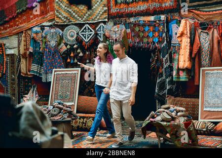 Ein Paar in Liebeswanderungen und Umarmungen auf dem östlichen Teppichmarkt. Ein Mann und eine Frau wählen einen türkischen Teppich Stockfoto