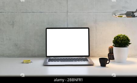Laptop auf dem Schreibtisch mit Werk, Schreibtischlampe, Kaffeetasse und 3D-Rendering aus Betonwand Stockfoto